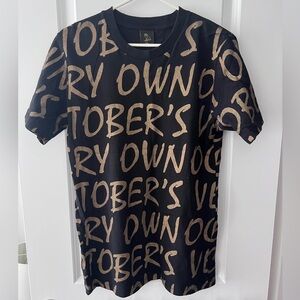 October's Very Own (OVO) all-over print t-shirt in black with gold text